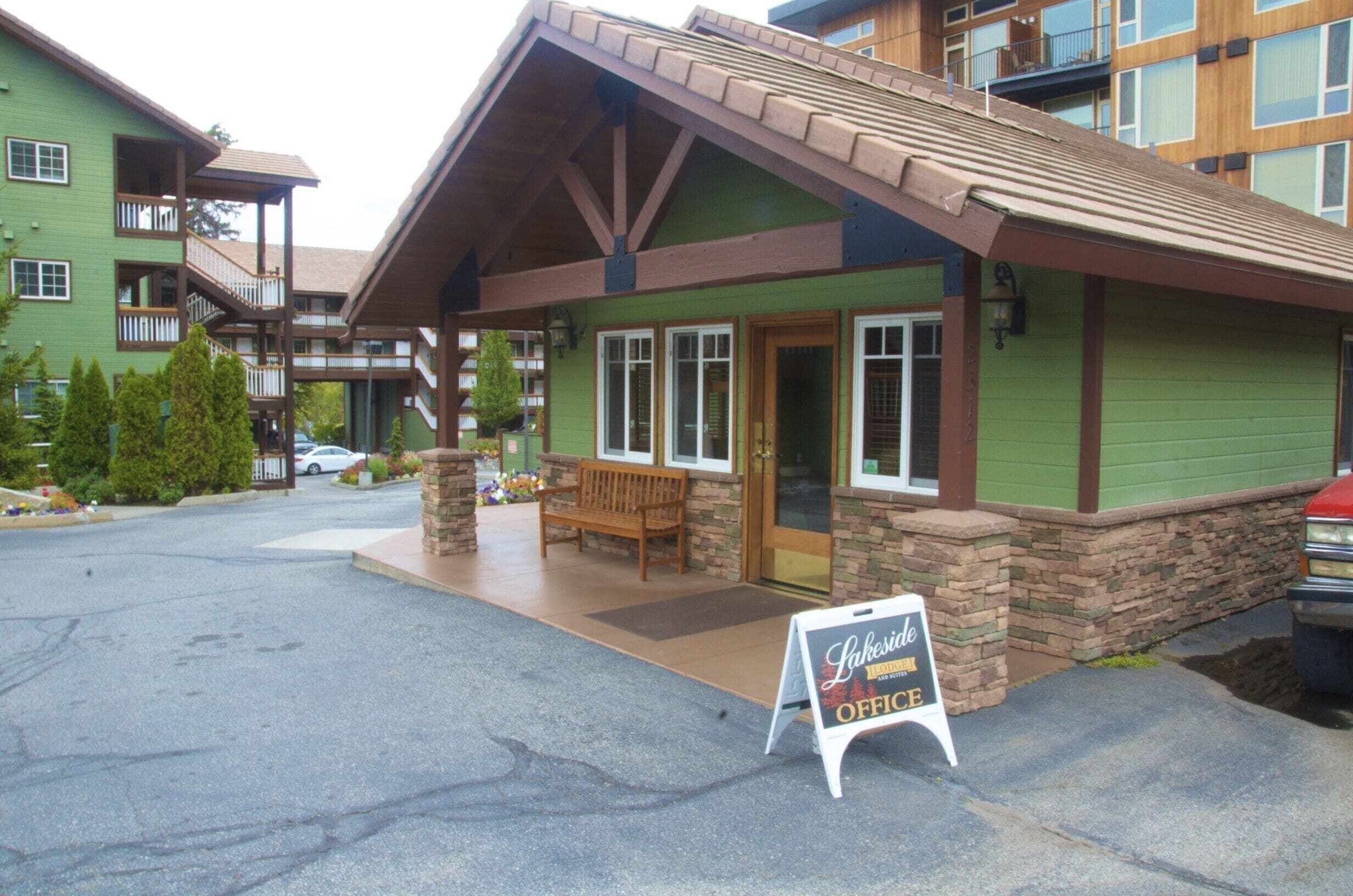 A building with a green exterior, a wooden porch, and a sign indicating an office.