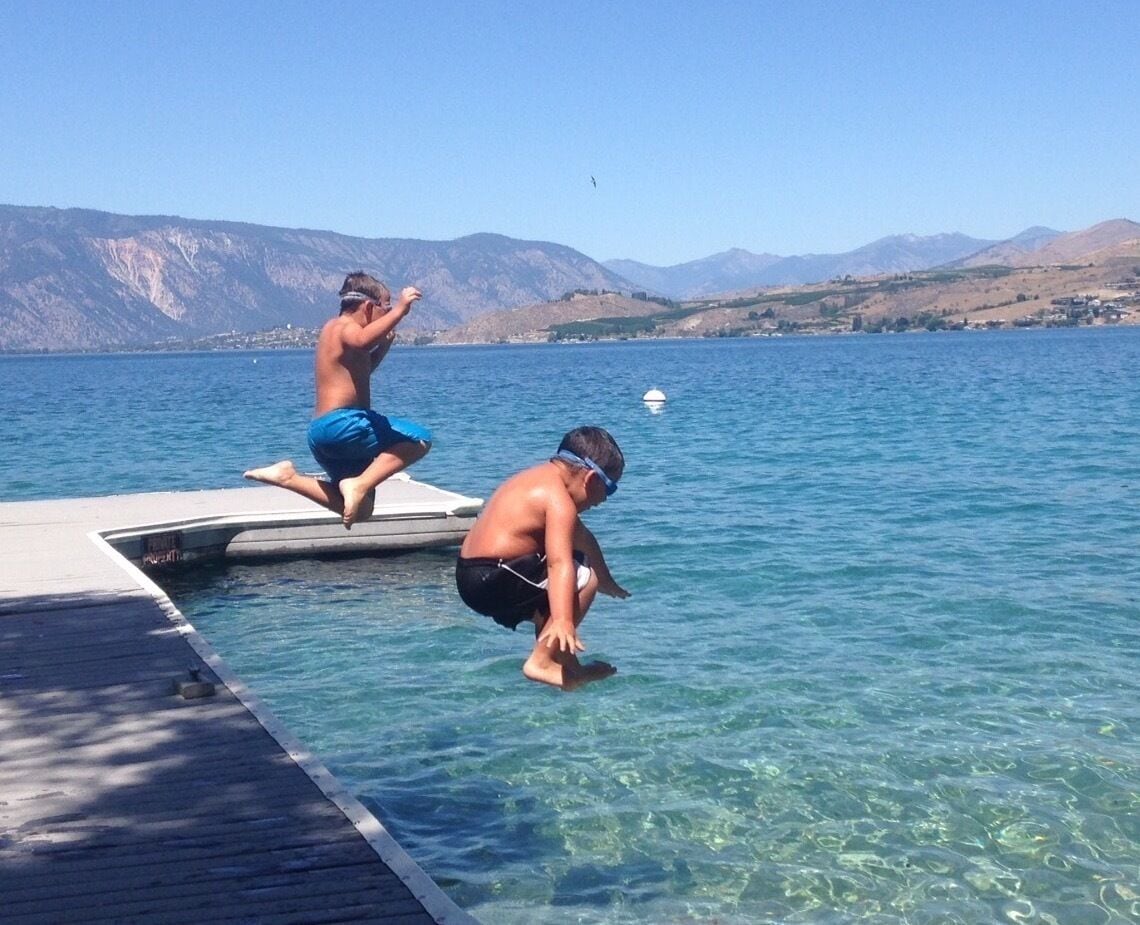 Deux personnes se tiennent sur une jetée qui s’avance dans un lac, avec des montagnes en arrière-plan.