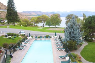 Una piscina con sillas de descanso, vistas a un lago y un paisaje montañoso al fondo.