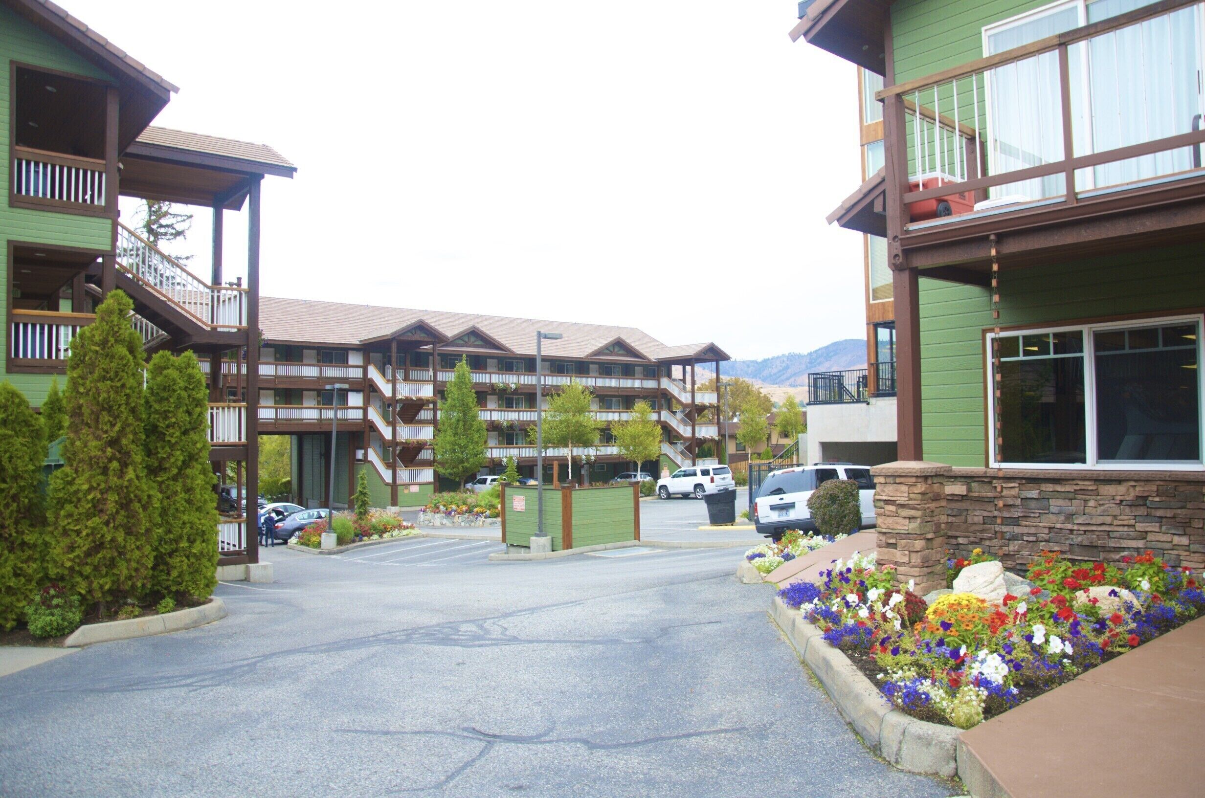 Un hotel de diverses plantes amb un pati central, seients exteriors i vista a la muntanya.