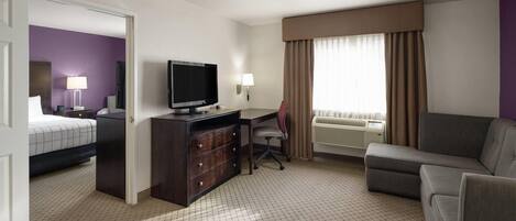 A hotel room with a bed, desk, television, and a sofa.