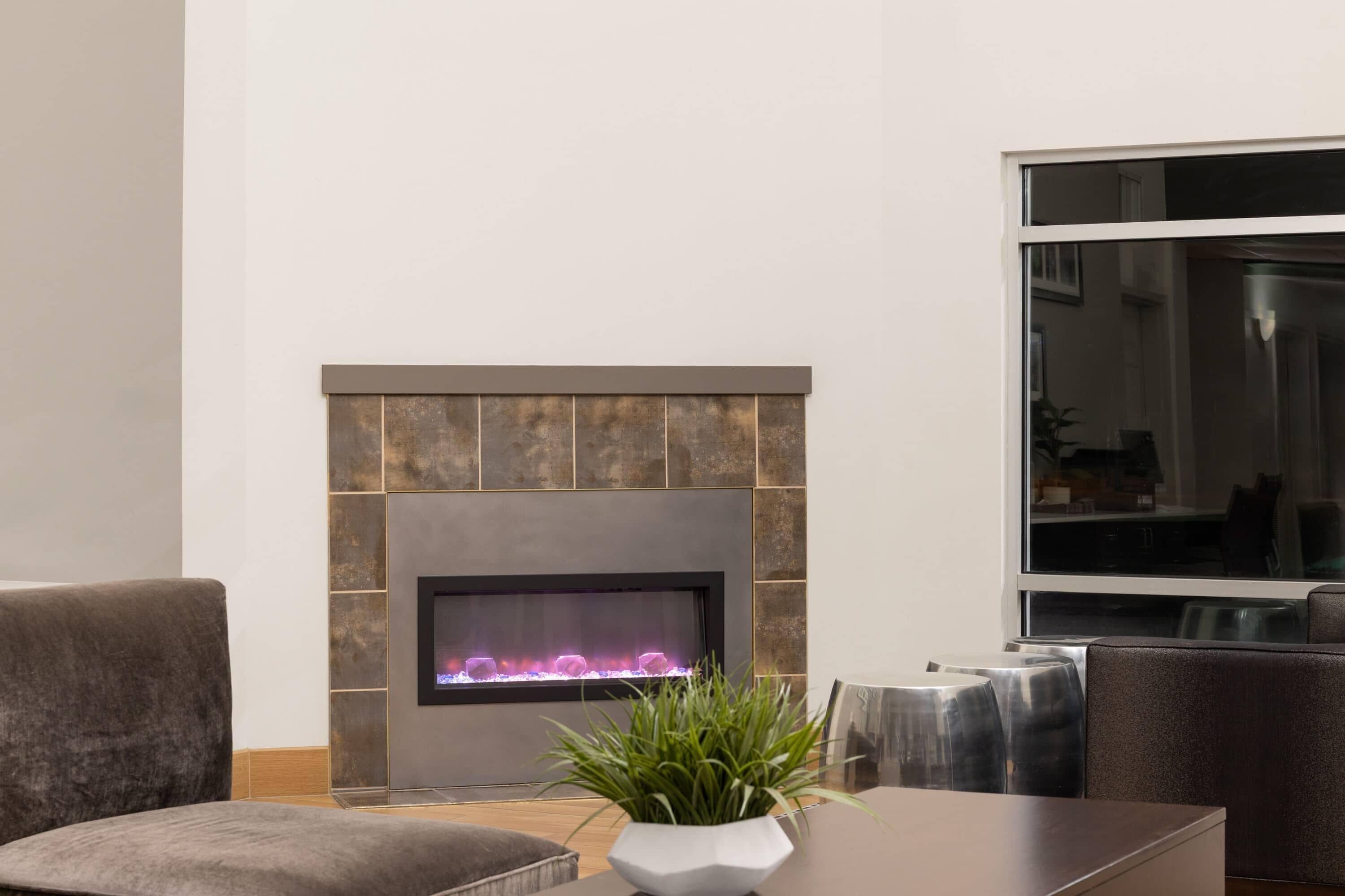 A modern living room with a fireplace, a comfortable seating area, and a large window.