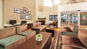 A modern living room with a fireplace, sofas, a coffee table, and artwork on the walls. - La Quinta Inn & Suites by Wyndham Spokane Valley (Spokane Valley)