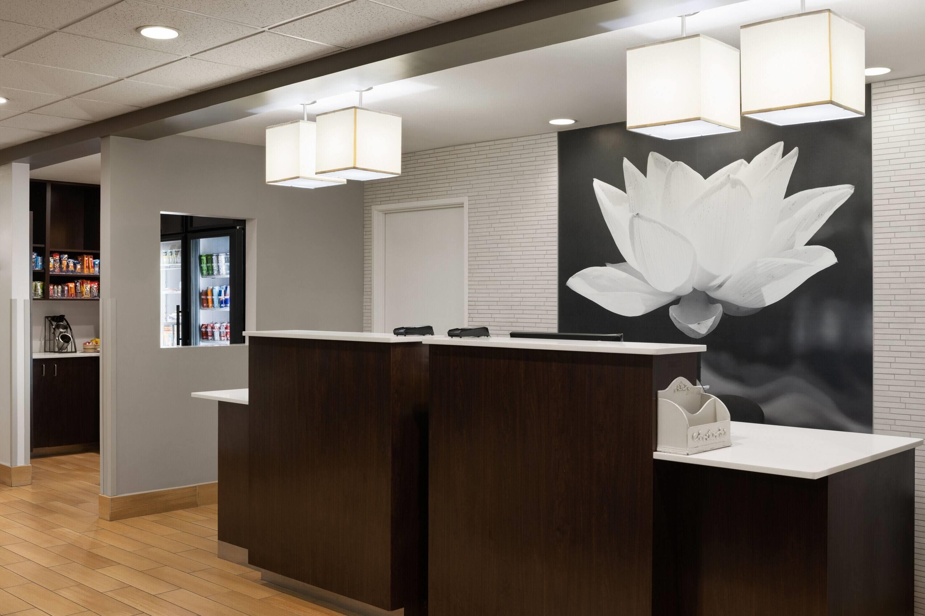 A reception desk with a white lotus mural, a dark wood reception desk, and a white counter.