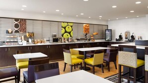 A modern restaurant with a counter, seating area, and kitchen in the background. - La Quinta Inn & Suites by Wyndham Spokane Valley (Spokane Valley)