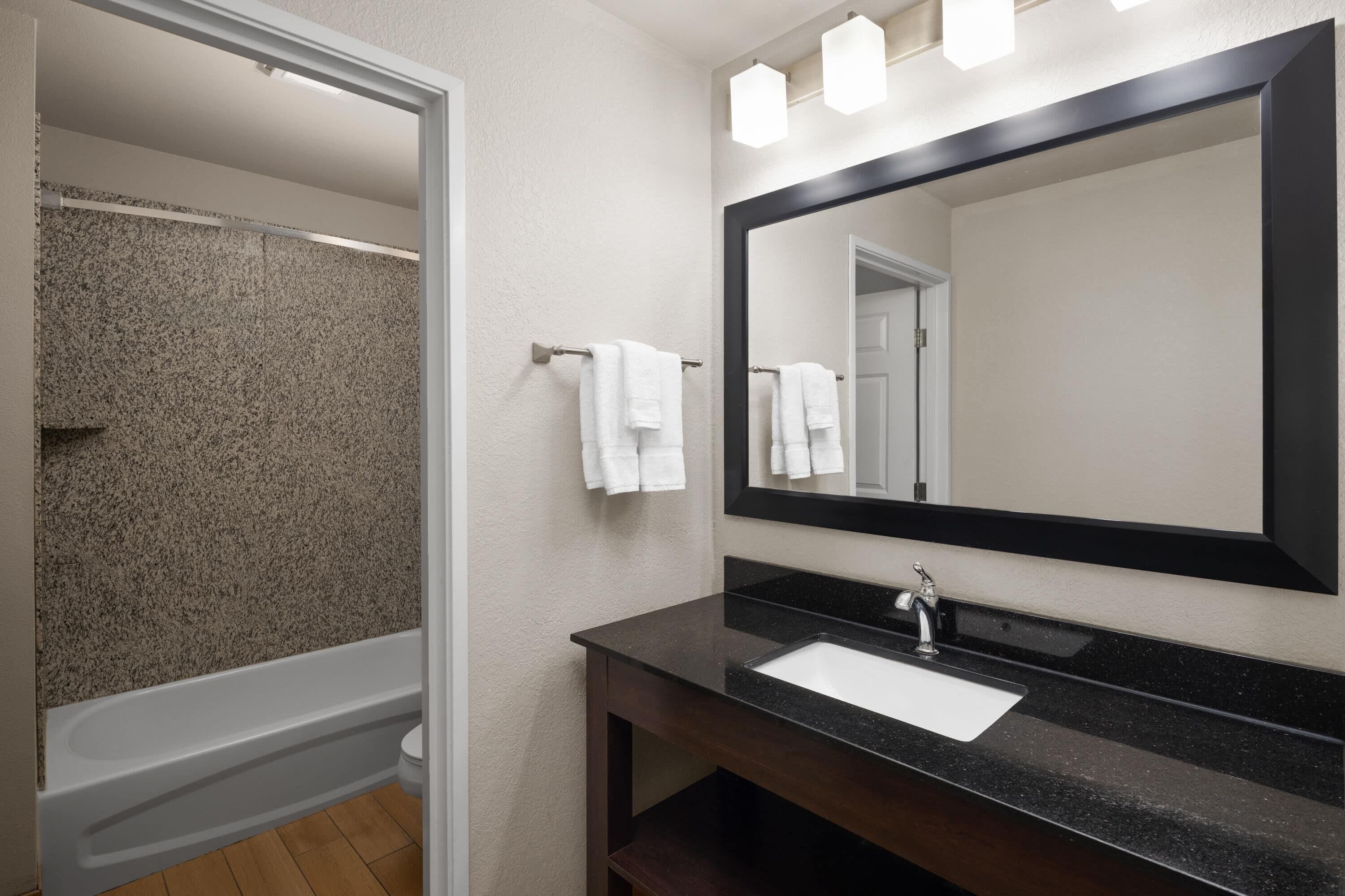 A bathroom with a bathtub, a sink, and a large mirror.