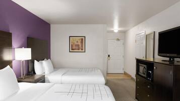 A hotel room with two beds, a TV, a microwave, and a cabinet.