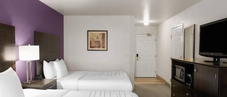 A hotel room with two beds, a TV, a microwave, and a cabinet.