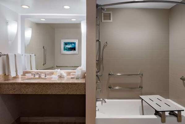 Un baño moderno con lavamanos, espejo e inodoro con ducha.
