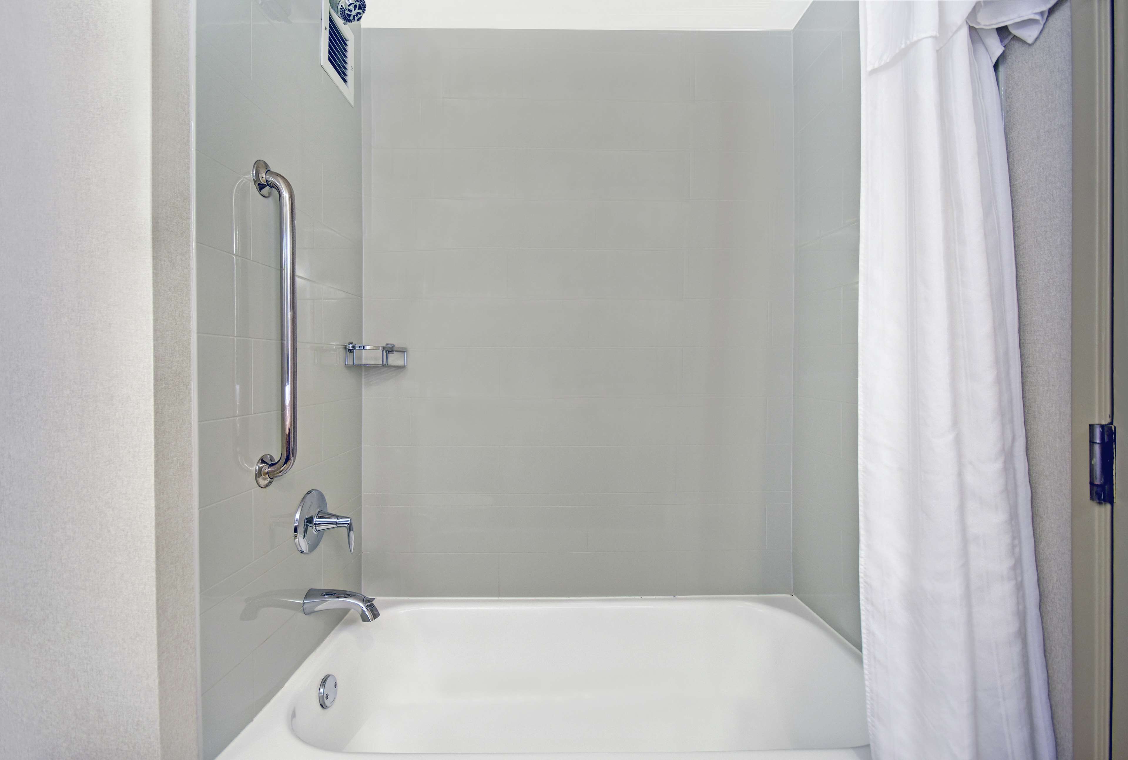 A bathroom with a shower, grab bar, and a bathtub.
