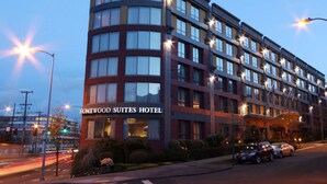 Een meerhoog hotel met een gebogen gevel, grote ramen en een bord waarop 'Homewood Suites Hotel' staat.