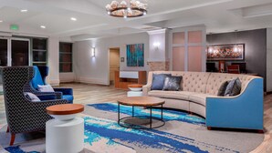 Een moderne lobby met een bank, fauteuil en een ronde salontafel.