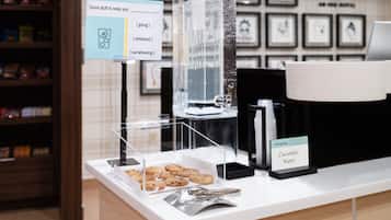 Un espace dédié au café, équipé d’un distributeur d’eau, d’une pancarte indiquant la présence d’eau aromatisée au concombre et d’un présentoir de biscuits.