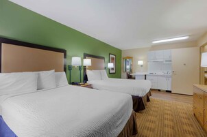 Habitación de hotel con dos camas, un kitchenette y un baño.