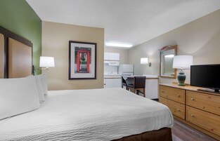A hotel room with a bed, a desk, a chair, a television, and a mirror.