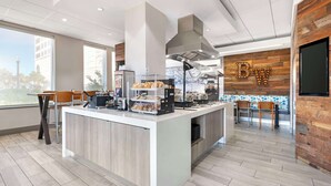 Um café moderno com balcão central, área de estar e parede de destaque em madeira com as letras 'BW'.
