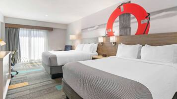 Habitación de hotel con dos camas, un escritorio, una silla, una lámpara y una decoración circular grande en la pared.