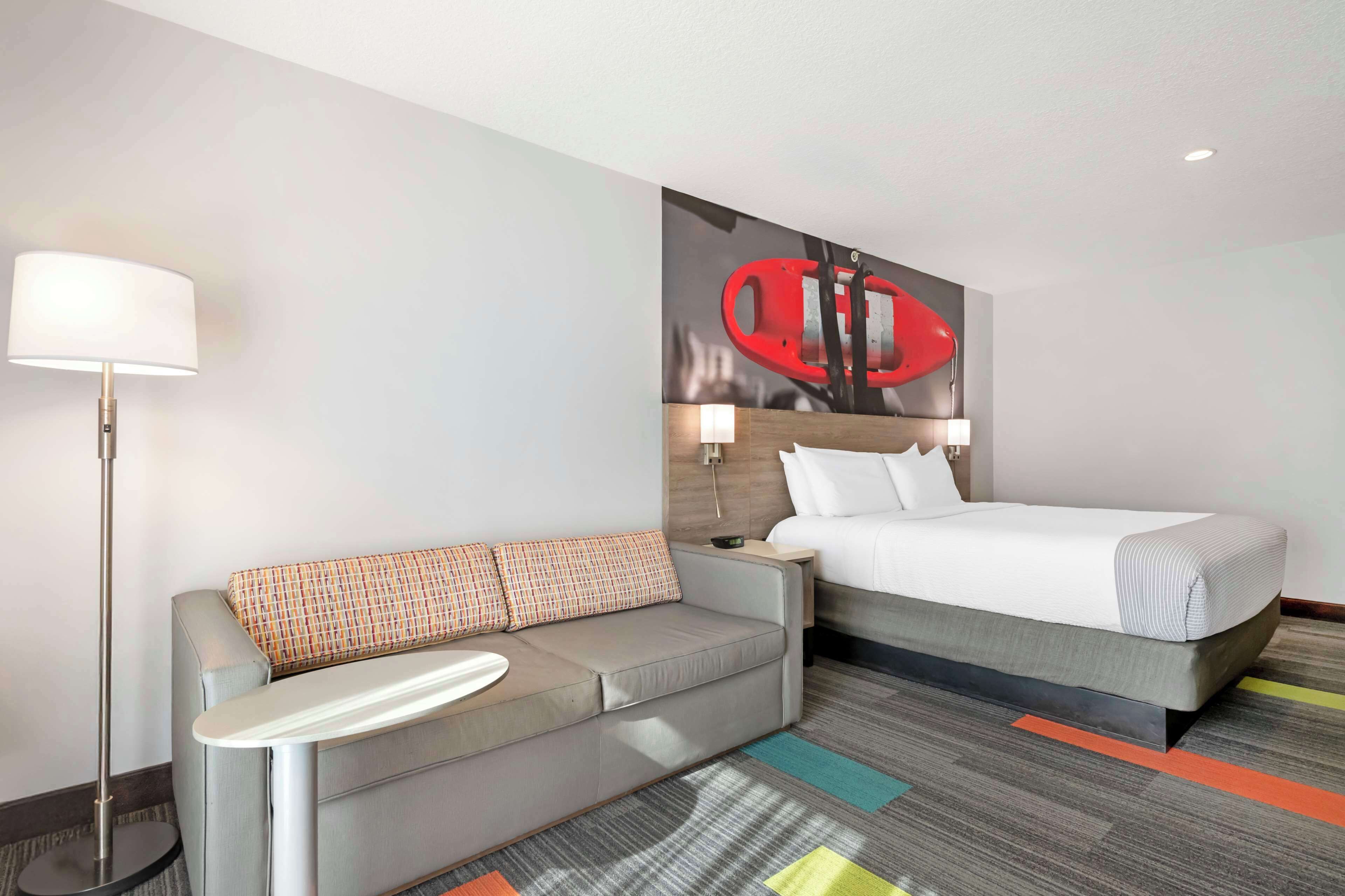 Una habitación de hotel con una cama, un sofá, una lámpara y una alfombra colorida.