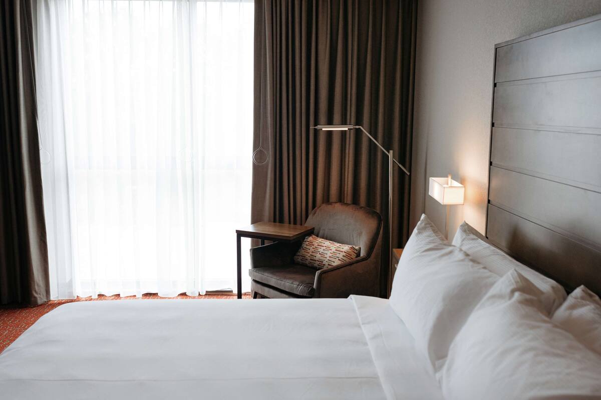 Ein Hotelzimmer mit einem großen Bett, einem Sessel, einem Tisch und einer Lampe.