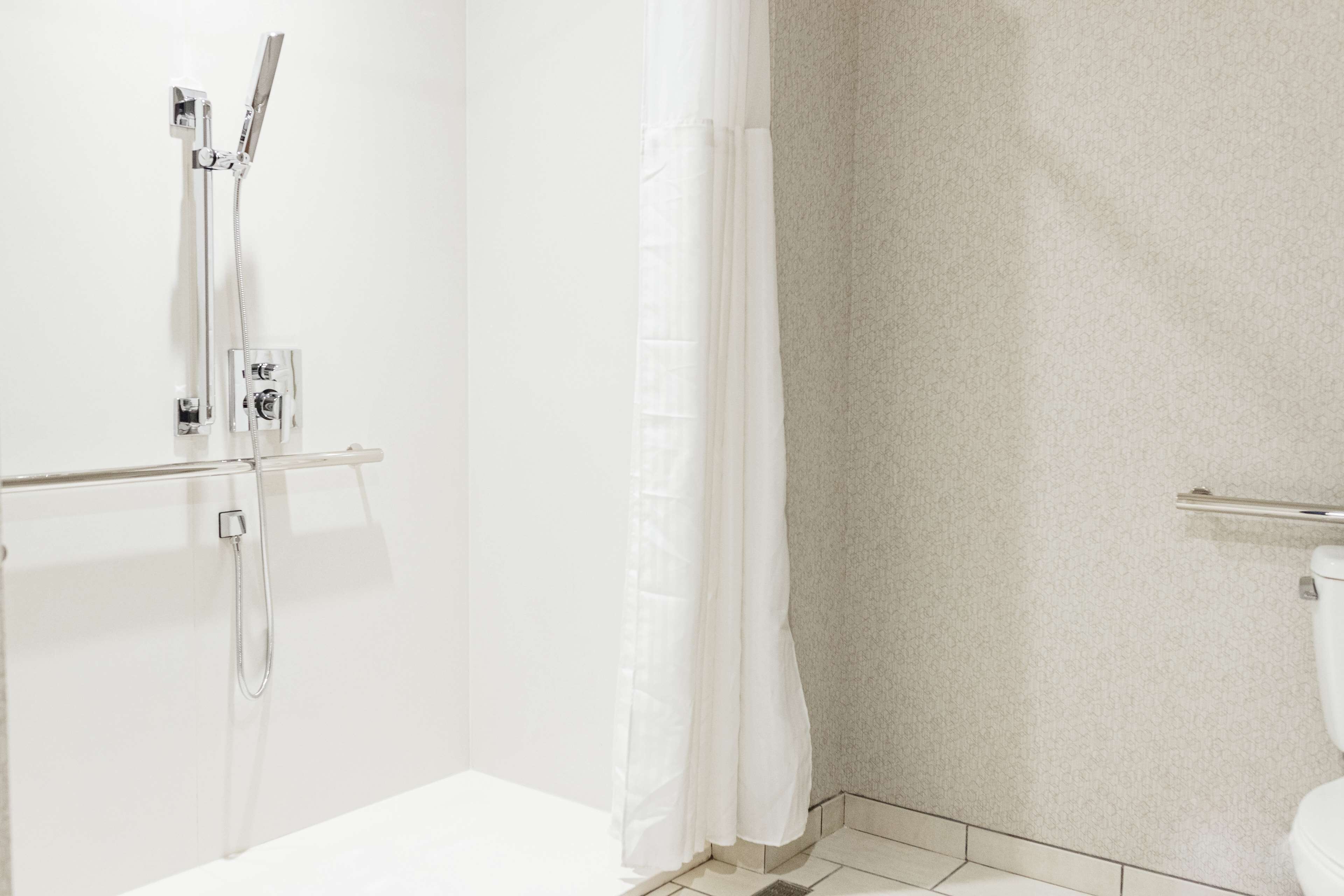 A bathroom with a shower, toilet, and a towel rack.