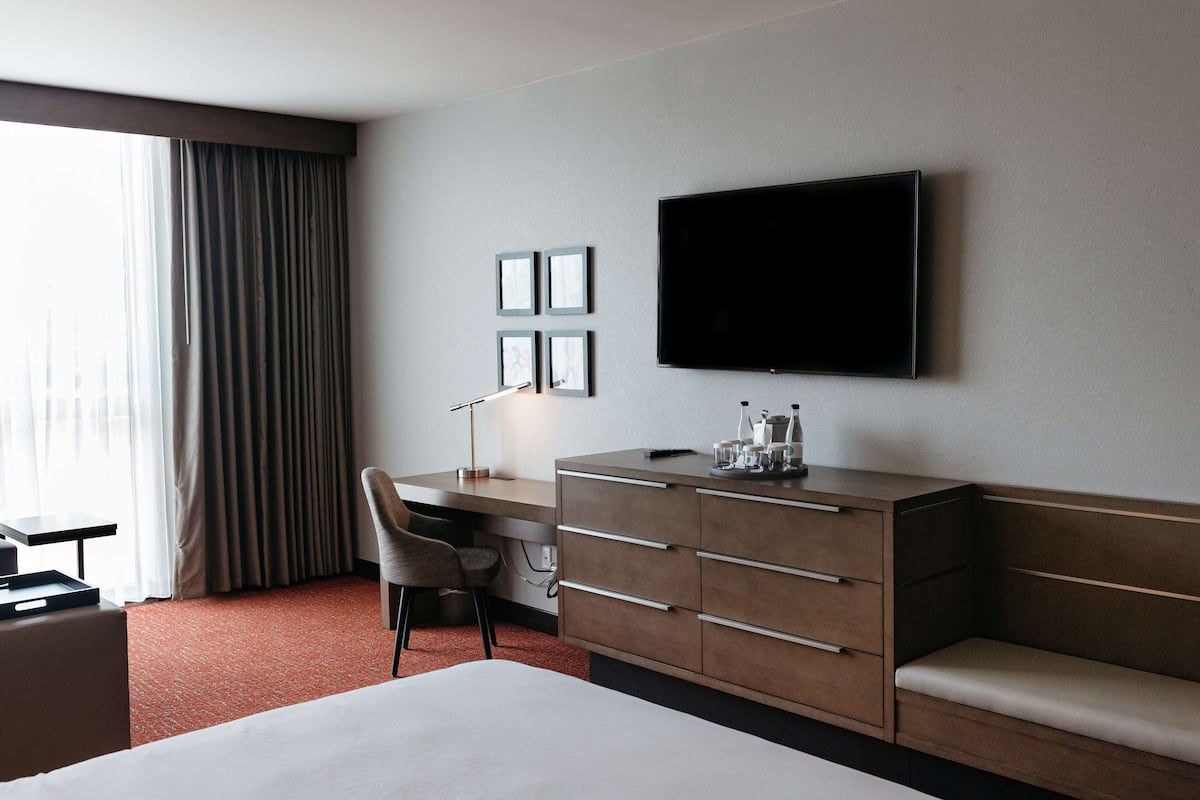 Ein Hotelzimmer mit Bett, Schreibtisch, Stuhl, Fernseher und Kommode.