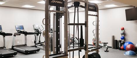 A gym with treadmills, a weightlifting station, and exercise balls.