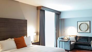 Une chambre d’hôtel avec un grand lit, un canapé, un bureau et une œuvre d’art accrochée au mur.