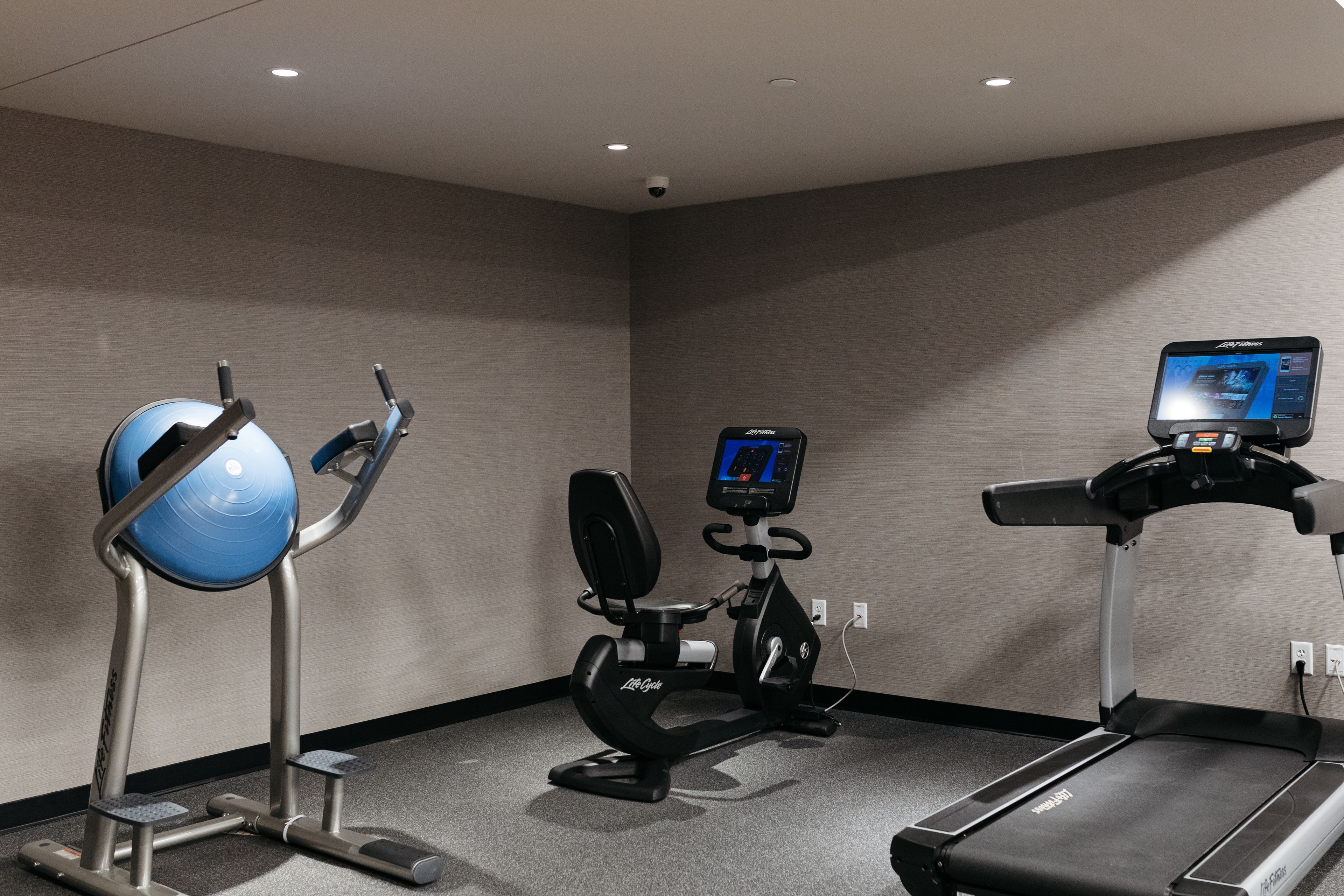 A fitness room with a treadmill, elliptical, and stationary bike.