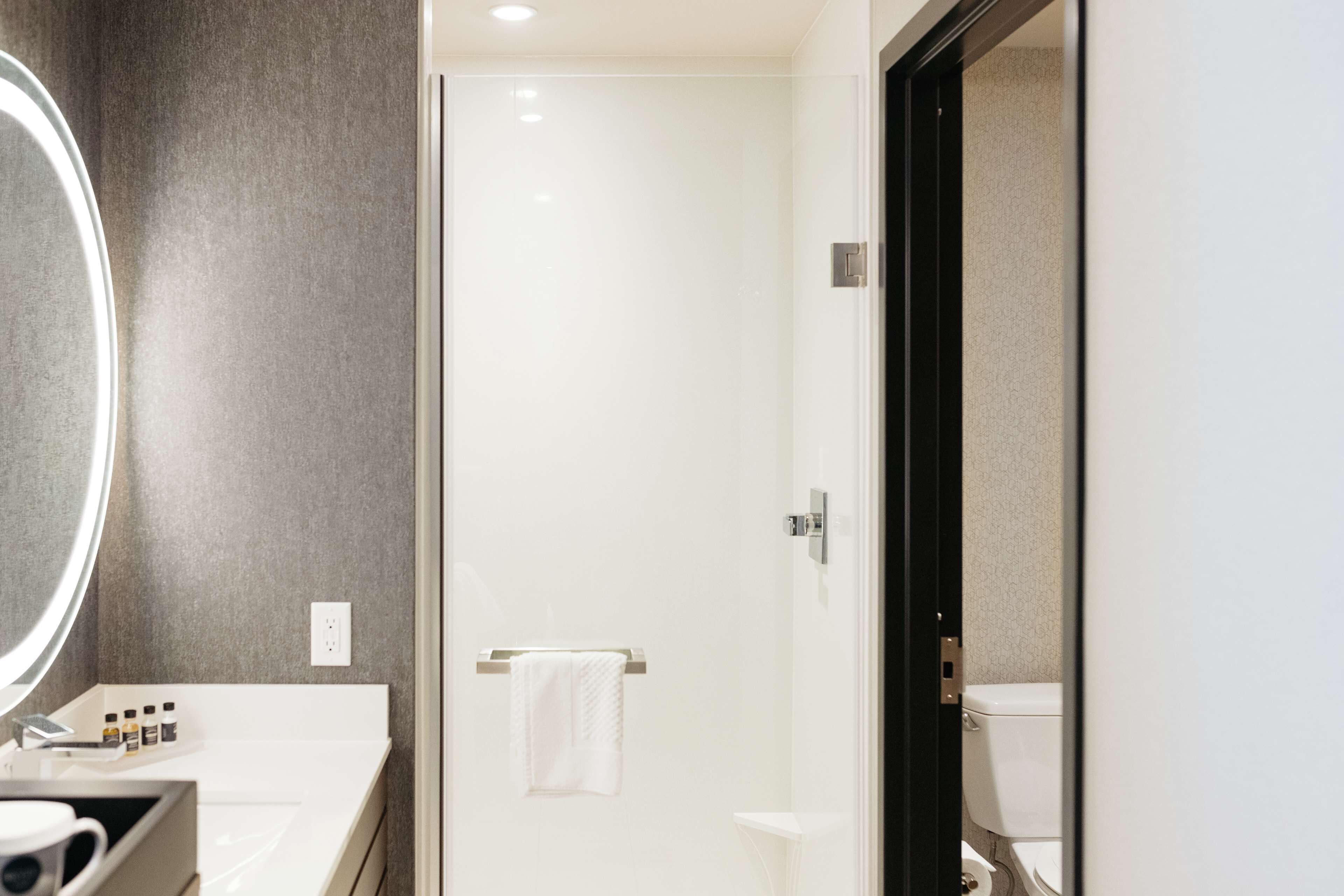 Un baño moderno con un lavabo blanco, un espejo y una cabina de ducha de vidrio.