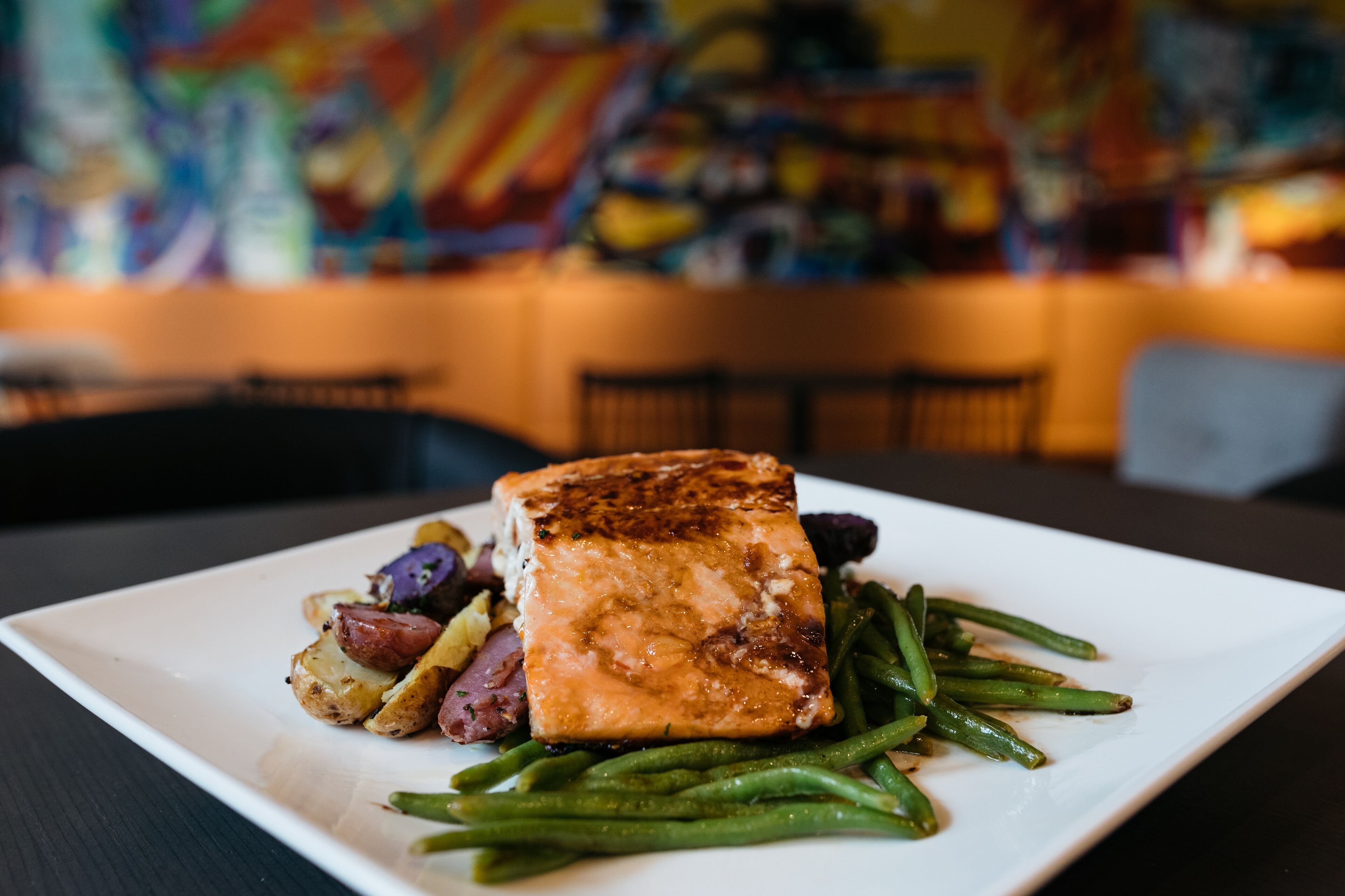 A plate of food with salmon, green beans, and potatoes on a white plate.