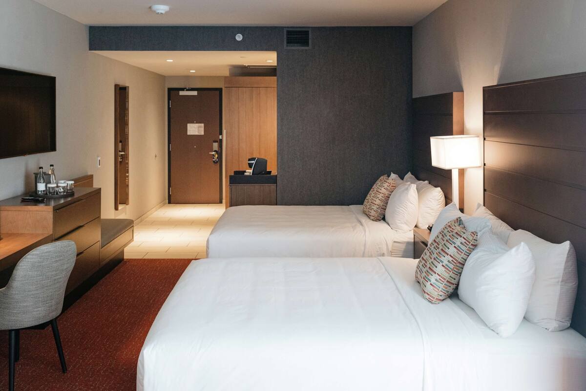 Ein Hotelzimmer mit zwei Betten, einem Schreibtisch, einem Stuhl, einem Fernseher und einer Lampe.