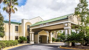 A hotel entrance with a covered driveway, palm trees, and a clear sky. - Quality Inn Darien - North Brunswick (Darien)