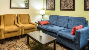 A hotel room with two armchairs, a sofa, a coffee table, and a lamp. - Quality Inn Darien - North Brunswick (Darien)