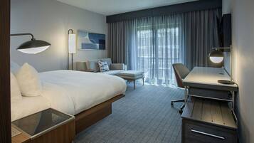 Une chambre d’hôtel moderne équipée d’un grand lit, d’un bureau, d’une chaise, d’une télévision et d’une fenêtre avec des rideaux.