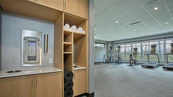 A modern gym with wooden cabinets, a coffee machine, and exercise equipment.