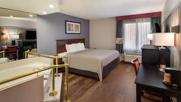 A hotel room with a bed, bedside table, lamp, and a television.
