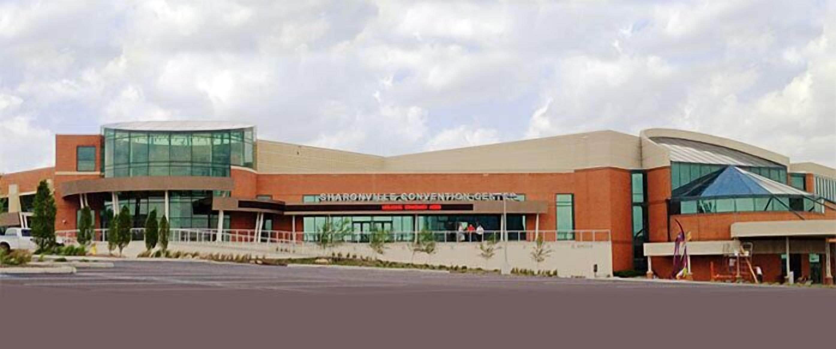 A modern convention center with a curved glass facade and a prominent sign.