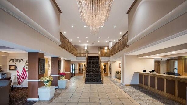 Un'ampia hall con una scalinata centrale, una reception e un lampadario.