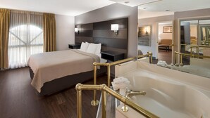 Camera d'albergo con un letto grande, una vasca da bagno e un'area salotto separata con un divano e un tavolino.