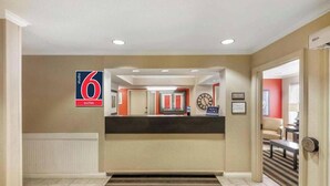 A hotel reception area with a reception desk, a clock, and a sign indicating 6 suites. - Studio 6 Extended Stay Milwaukee Brookfield WI (Brookfield)