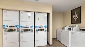 A laundry area with six stacked washers and dryers, each with a digital control panel.