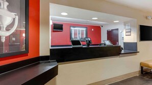 A reception desk with a red wall, a black counter, and a framed picture.