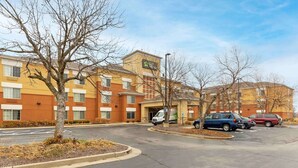 A hotel with a parking lot, a tree-lined driveway, and a building with a yellow facade.