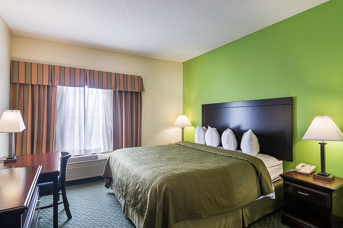 A hotel room with a bed, two bedside lamps, a desk, and a chair.