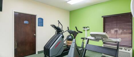 Ein Fitnessraum mit zwei Laufbändern, einem Ergometer und einem Rudergerät.