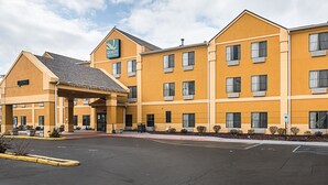 A multi-story hotel with a yellow facade, a covered entrance, and a parking lot. - Quality Inn & Suites Harvey - Chicago Southland (Harvey)