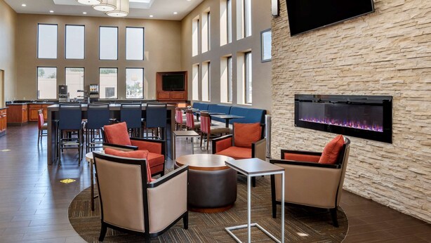 A spacious hotel lobby with a bar area, seating arrangements, and a large TV screen. - Comfort Suites Hagerstown Southeast (Hagerstown)