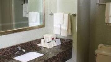 A bathroom with a granite countertop, a sink, a mirror, a toilet, and a towel rack.