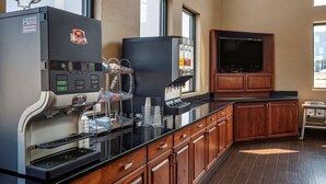 A coffee station with a branded machine, a television, and wooden cabinets. - Comfort Suites Hagerstown Southeast (Hagerstown)