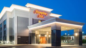 Eingangsbereich eines Hampton Inn Hotels mit gut sichtbarer Beschilderung, überdachtem Außenbereich und einladendem Eingang.